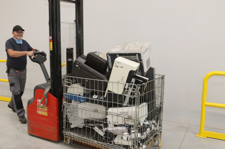 travailleur en situation de handicap qui pousse un chariot avec du matériel informatique à recycler